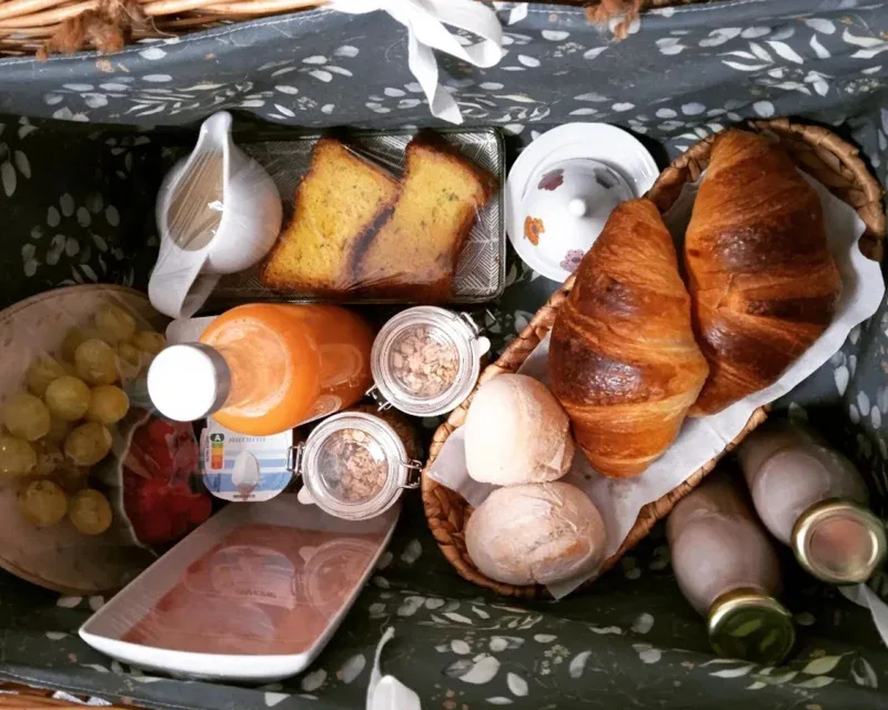 Cesta de pequeno-almoço com pão, croissants, fruta e sumo